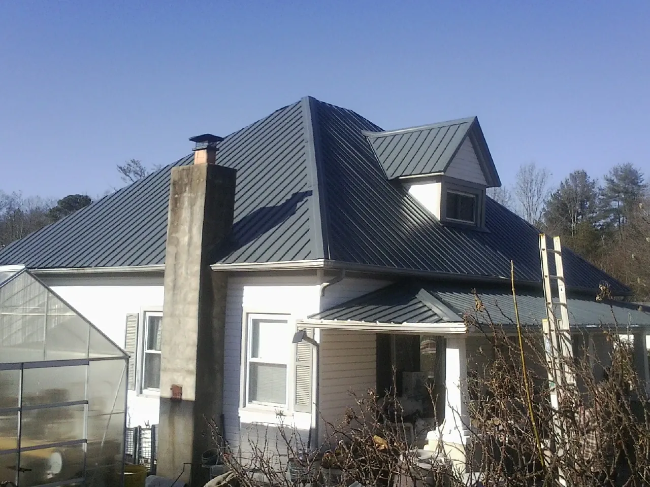 Dark blue standing seam metal roof on a white farmhouse with dormer — Slate & Tile Roof Repair by Roofing Brothers in Glen Spey