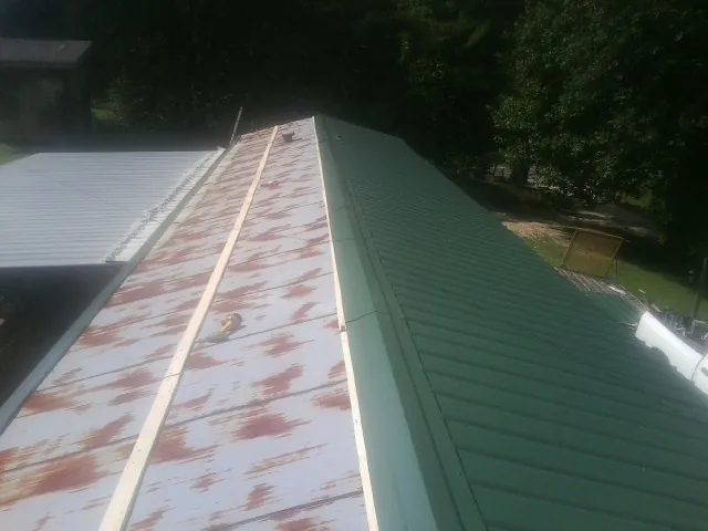 Old rusted panels beside newly installed green metal roofing — Wind Damage Roof Repair by Roofing Brothers in Glen Spey