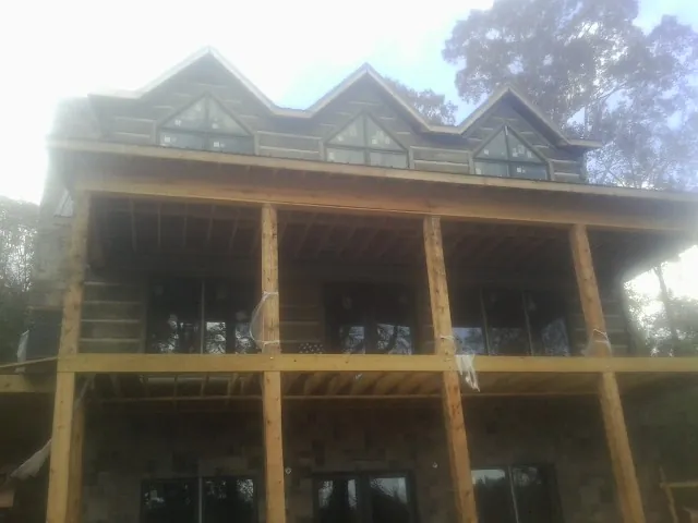 Dormers and porch framing on a large log home under construction — Roof Coating work by our crew in Glen Spey