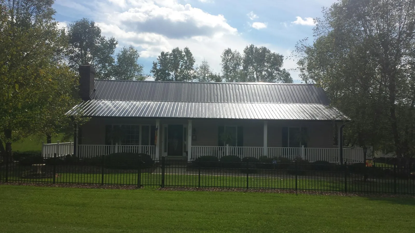 Gray metal roof on a brick ranch with a full width front porch — Gutter Guard Installation work by our crew in Glen Spey