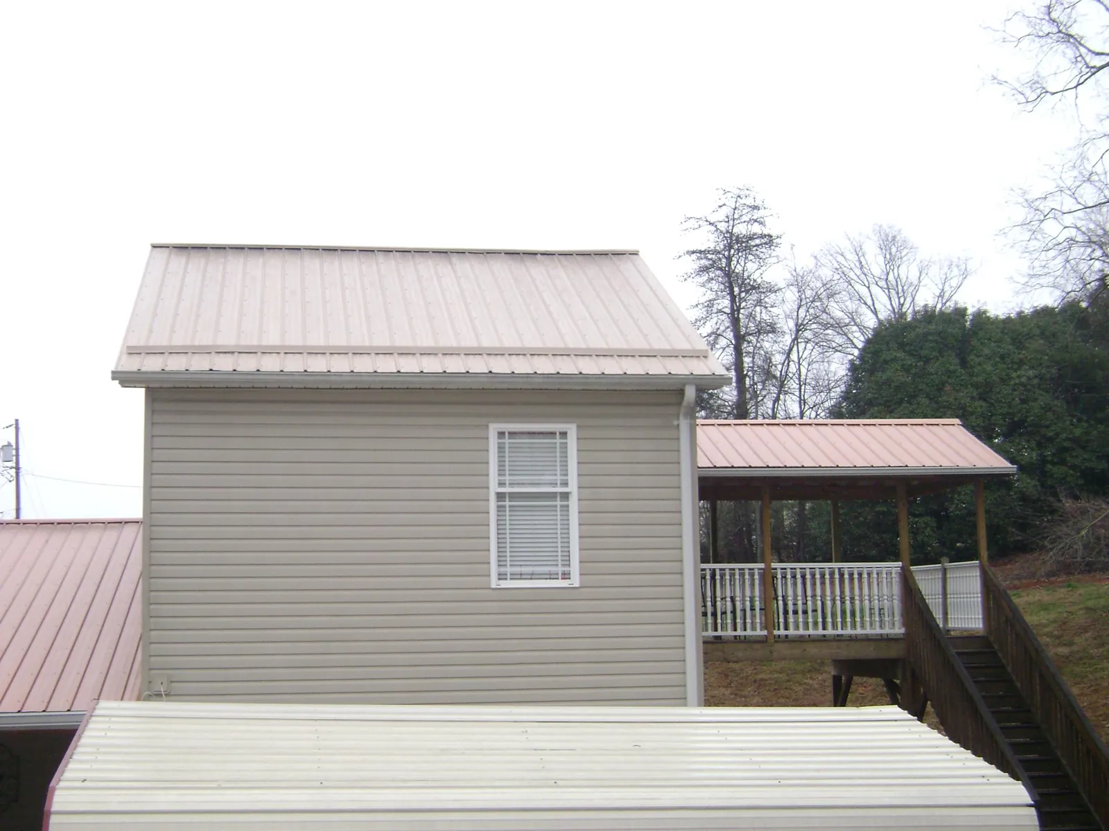 Tan metal roofs on a two story addition and attached porch, from a Roof Replacement job in Glen Spey
