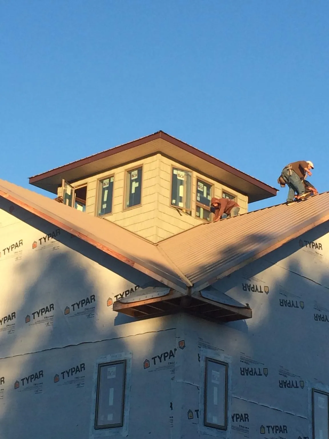Roofers working around a rooftop cupola on a new metal roof at sunset — Roof Waterproofing in Glen Spey by Roofing Brothers